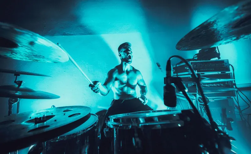 Garret behind the kit, shouting, sticks mid-air between the cymbals